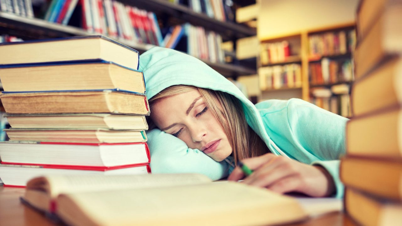 people, education, session, exams and school concept - tired student girl or young woman with books sleeping in library